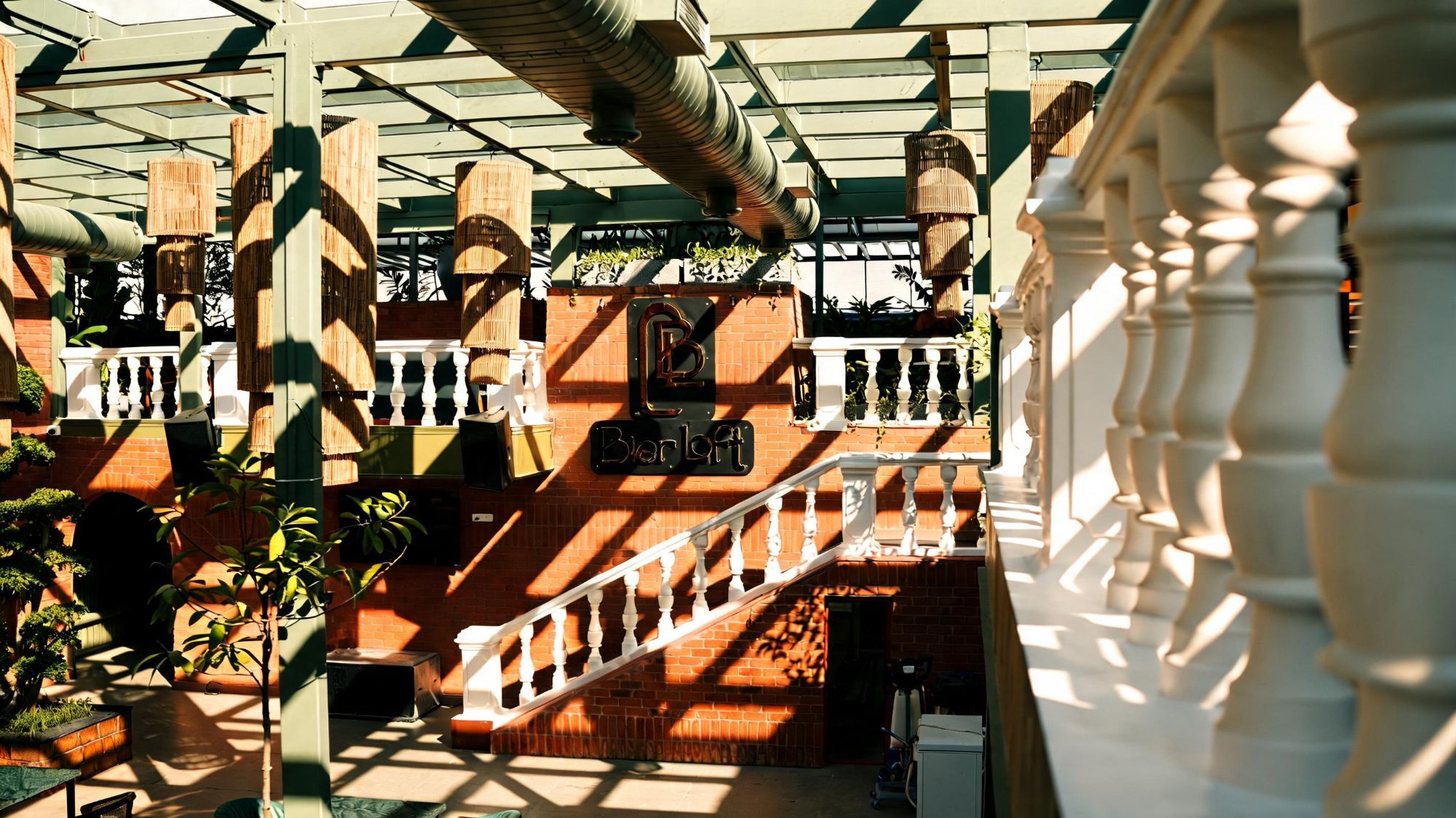 White balustrade staircase and Bier Loft logo on the brick wall in afternoon light